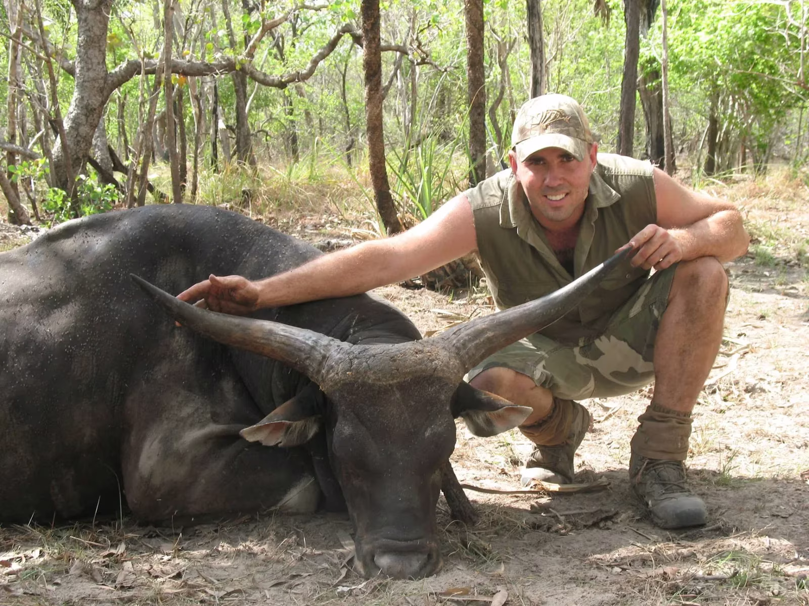 Hunter beside a buffalo bull taken in thick timber