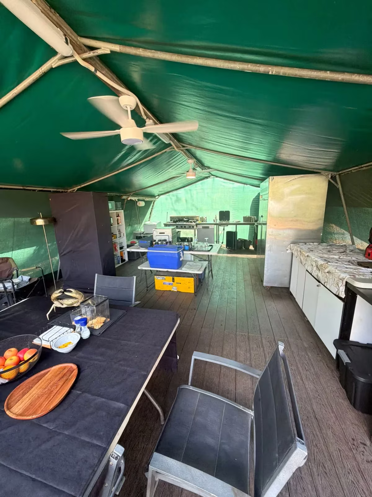 Inside the mess tent — dining table, kitchen and ceiling fans