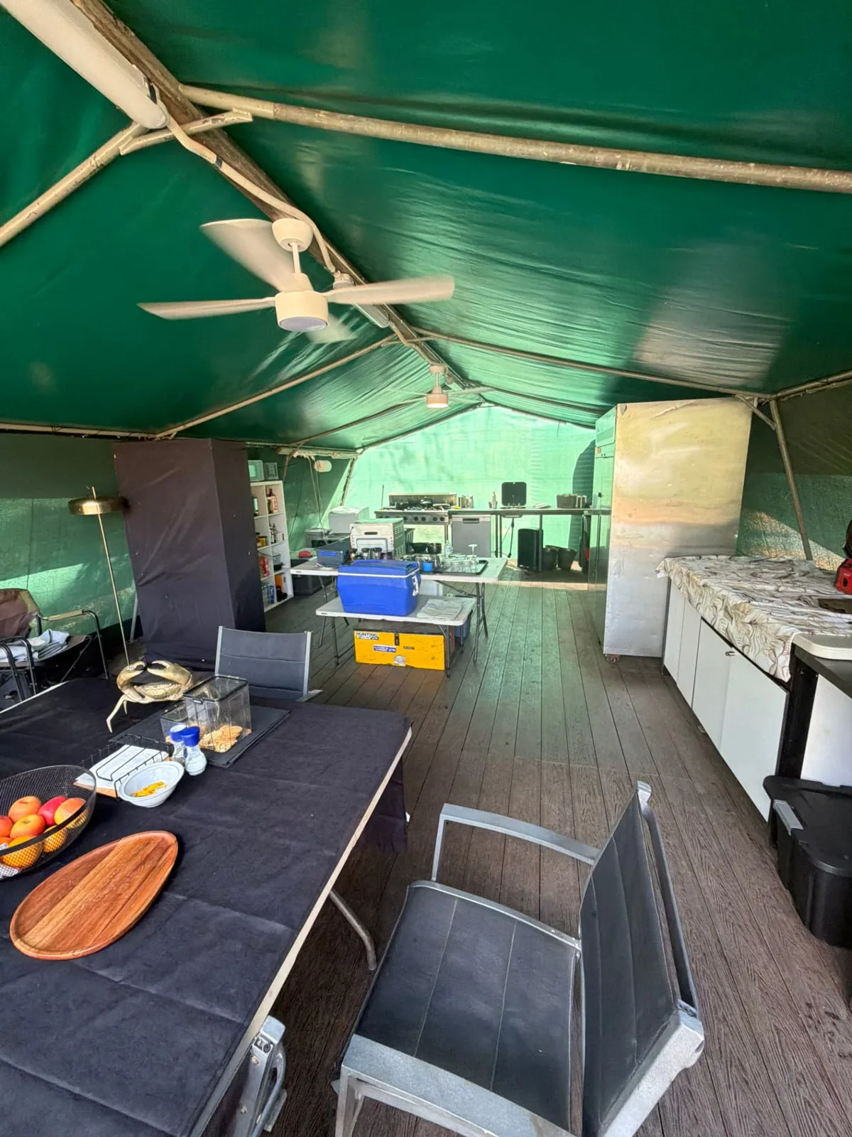 Inside the mess tent — dining table, kitchen and ceiling fans