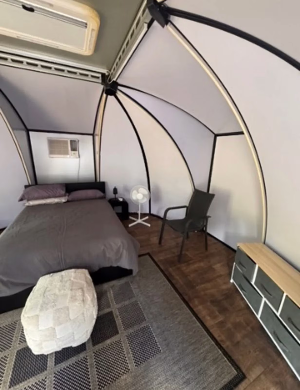Inside a camp pod — queen bed, air conditioning and timber floor