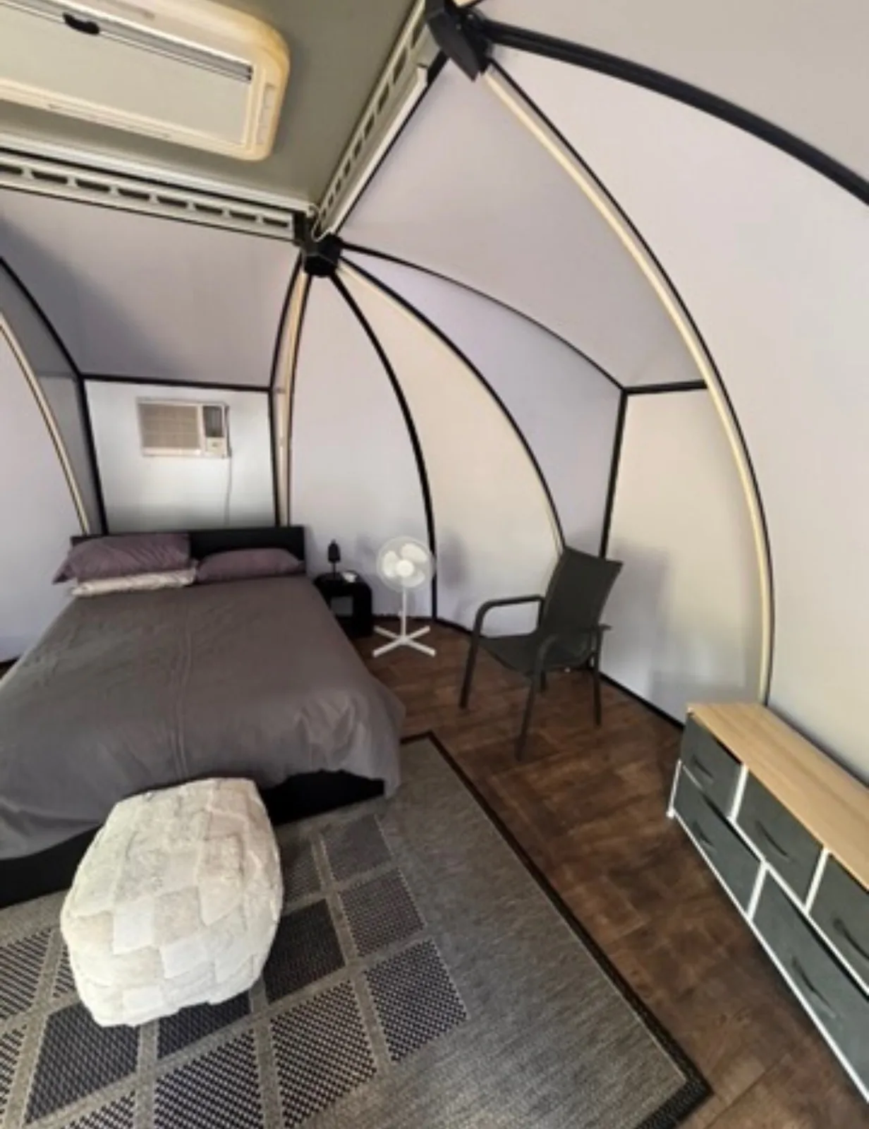 Inside a camp pod — queen bed, air conditioning and timber floor